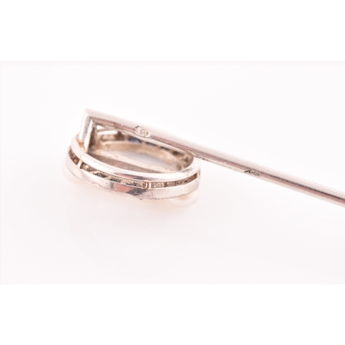 32 - Cartier. A white gold, diamond, and sapphire stick pin, the circular mount inset with calibre-set sa... 