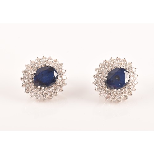 64 - A pair of 14ct white gold, diamond, and sapphire cluster earrings, each set with a mixed oval-cut sa... 