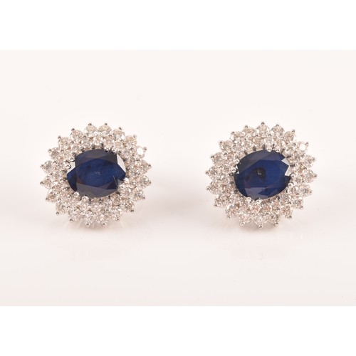 64 - A pair of 14ct white gold, diamond, and sapphire cluster earrings, each set with a mixed oval-cut sa... 