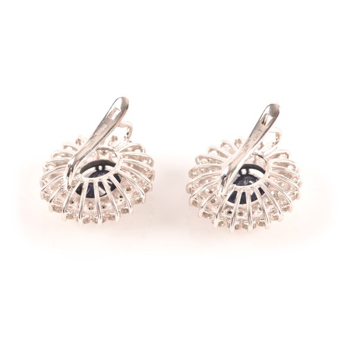 64 - A pair of 14ct white gold, diamond, and sapphire cluster earrings, each set with a mixed oval-cut sa... 