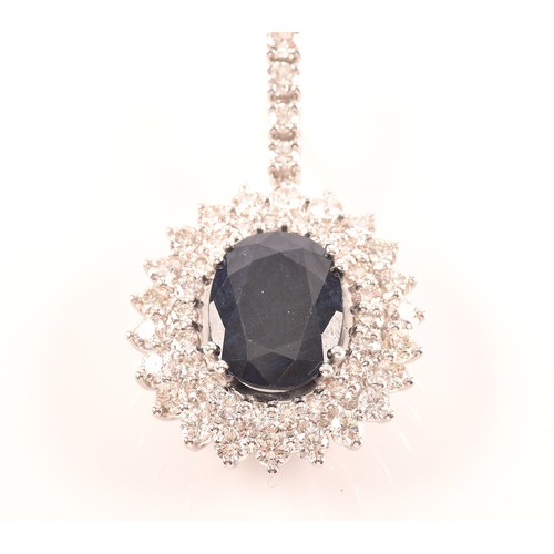 65 - A diamond and sapphire cluster pendant, set with a mixed oval-cut sapphire, measuring approximately ... 