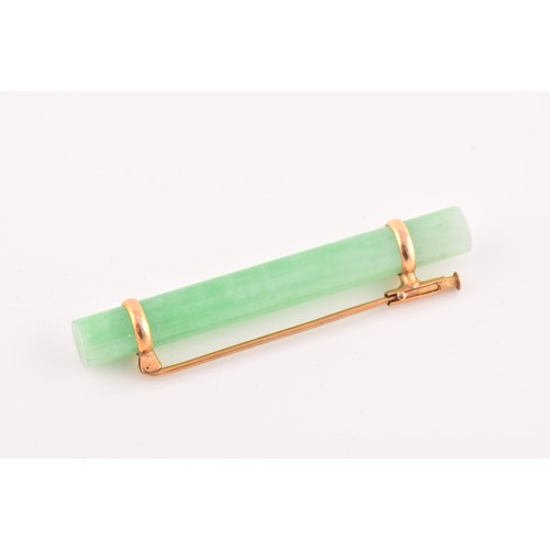 66 - A yellow metal mounted jade bar brooch, set with a polished green jade baton 5.8 cm long, mount unma... 