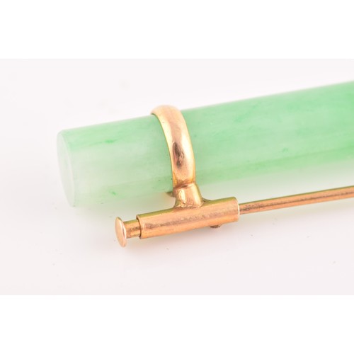 66 - A yellow metal mounted jade bar brooch, set with a polished green jade baton 5.8 cm long, mount unma... 