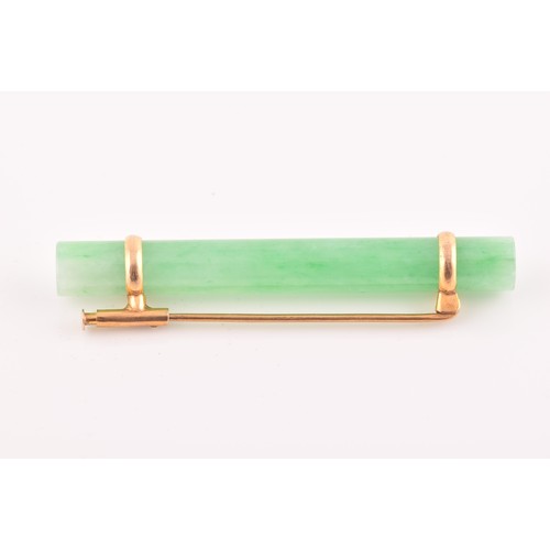 66 - A yellow metal mounted jade bar brooch, set with a polished green jade baton 5.8 cm long, mount unma... 