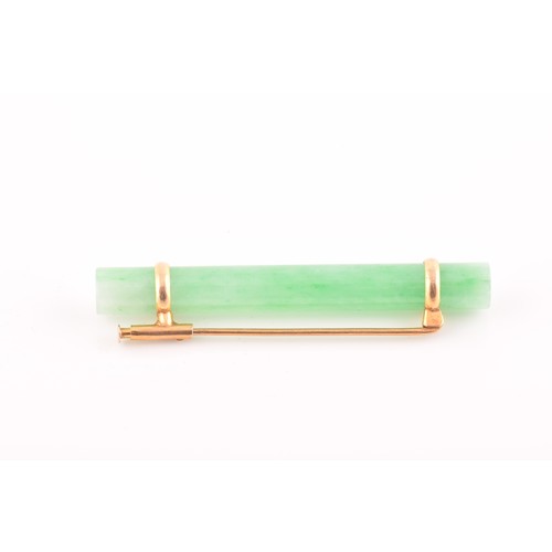 66 - A yellow metal mounted jade bar brooch, set with a polished green jade baton 5.8 cm long, mount unma... 