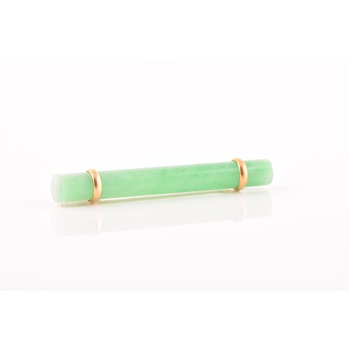 66 - A yellow metal mounted jade bar brooch, set with a polished green jade baton 5.8 cm long, mount unma... 