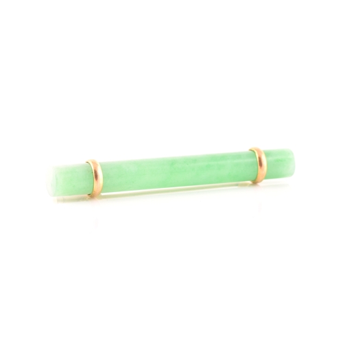 66 - A yellow metal mounted jade bar brooch, set with a polished green jade baton 5.8 cm long, mount unma... 