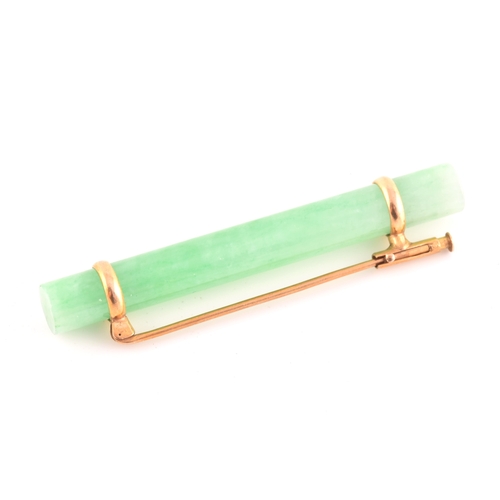 66 - A yellow metal mounted jade bar brooch, set with a polished green jade baton 5.8 cm long, mount unma... 