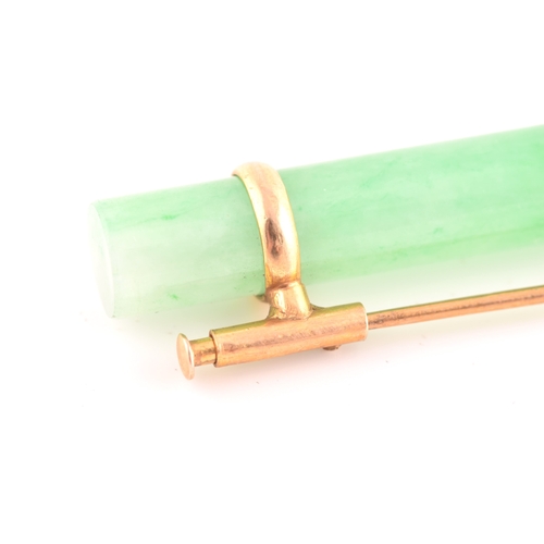 66 - A yellow metal mounted jade bar brooch, set with a polished green jade baton 5.8 cm long, mount unma... 