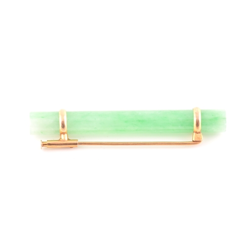 66 - A yellow metal mounted jade bar brooch, set with a polished green jade baton 5.8 cm long, mount unma... 