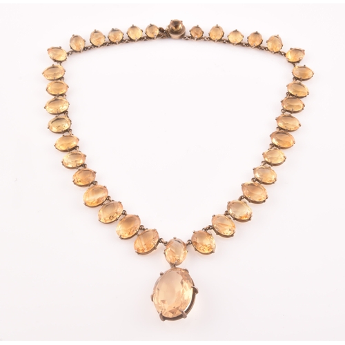 77 - A citrine riviere necklace, claw-set in silver gilt mount, the large mixed oval-cut drop measuring a... 