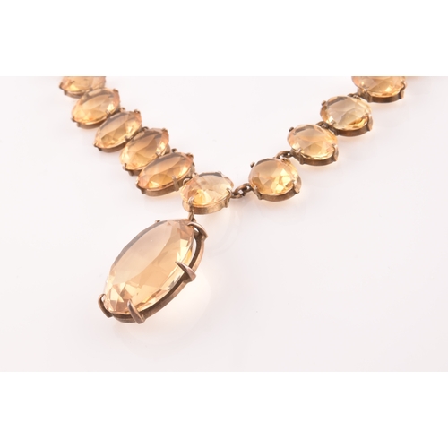 77 - A citrine riviere necklace, claw-set in silver gilt mount, the large mixed oval-cut drop measuring a... 