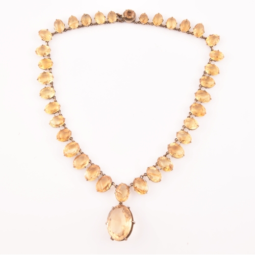 77 - A citrine riviere necklace, claw-set in silver gilt mount, the large mixed oval-cut drop measuring a... 