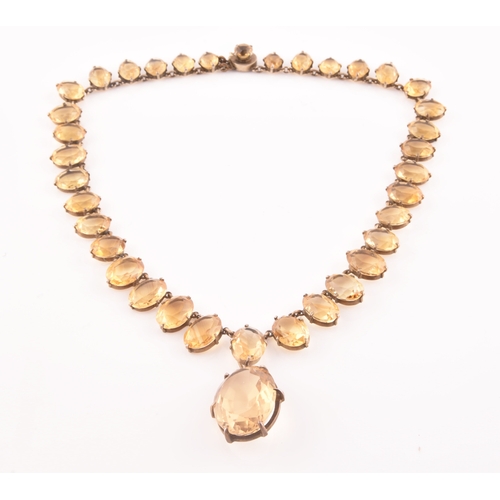 77 - A citrine riviere necklace, claw-set in silver gilt mount, the large mixed oval-cut drop measuring a... 