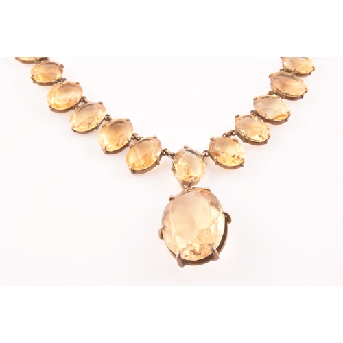 77 - A citrine riviere necklace, claw-set in silver gilt mount, the large mixed oval-cut drop measuring a... 