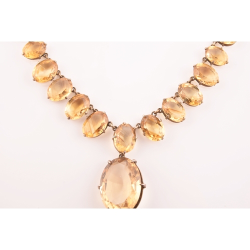 77 - A citrine riviere necklace, claw-set in silver gilt mount, the large mixed oval-cut drop measuring a... 