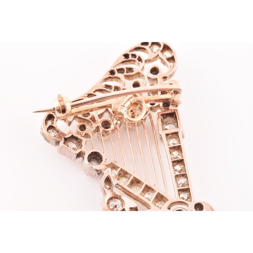 84 - A late 19th / early 20th diamond harp brooch, the scrolled decorative mount inset with mixed old-cut... 