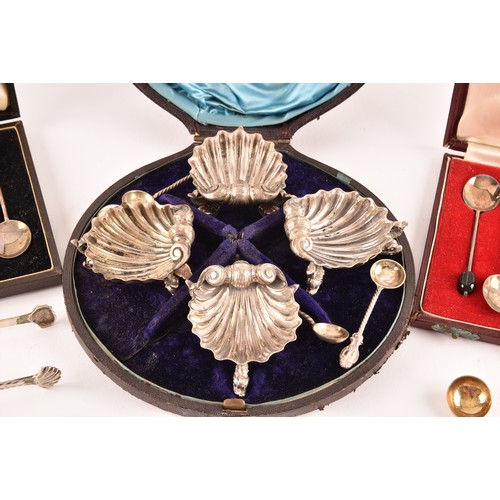 180 - A collection of silver items including a set of four shell shaped salts, silver cased coffee bean en... 