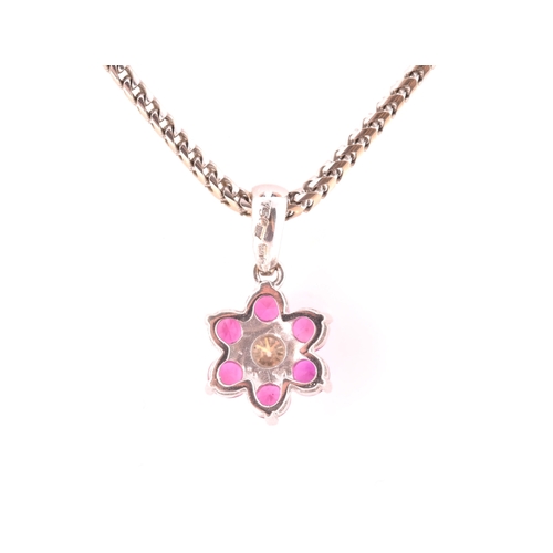 101 - An 18ct white gold, diamond, and ruby floral cluster pendant, centred with a round brilliant-cut dia... 