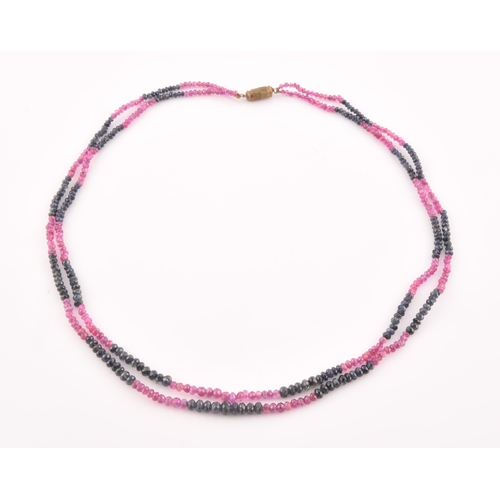 103 - A double strand necklace of faceted ruby and sapphire beads, approximately 45 cm long, fastened with... 