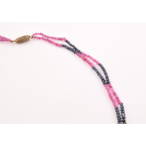 103 - A double strand necklace of faceted ruby and sapphire beads, approximately 45 cm long, fastened with... 