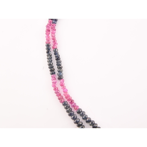 103 - A double strand necklace of faceted ruby and sapphire beads, approximately 45 cm long, fastened with... 