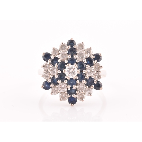 104 - An 18ct white gold, diamond, and sapphire starburst cluster ring, centred with a round brilliant-cut... 