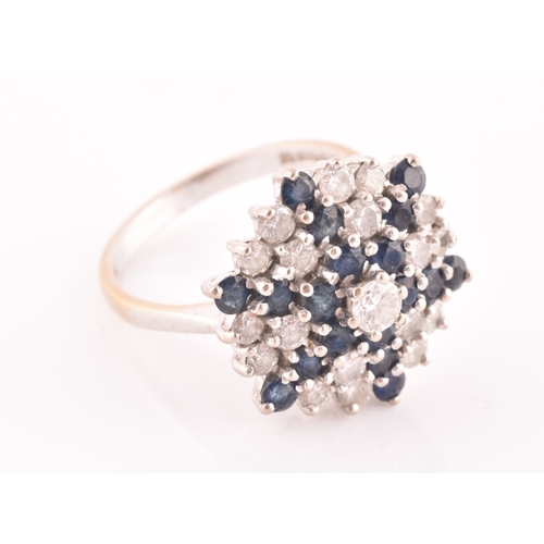 104 - An 18ct white gold, diamond, and sapphire starburst cluster ring, centred with a round brilliant-cut... 