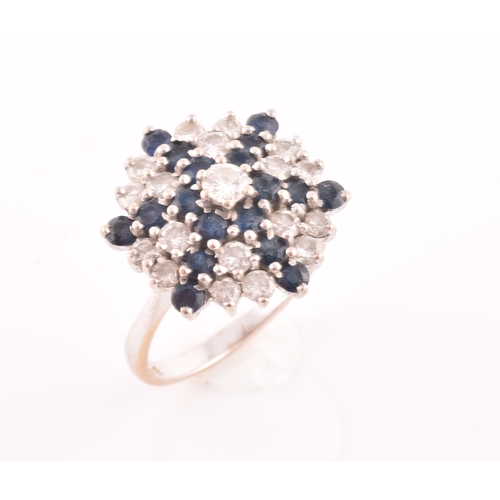 104 - An 18ct white gold, diamond, and sapphire starburst cluster ring, centred with a round brilliant-cut... 