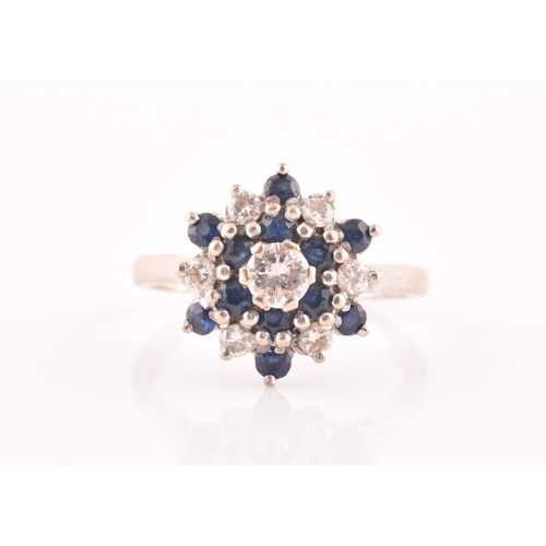 105 - An 18ct white gold, diamond, and sapphire cluster ring, centred with a round brilliant-cut diamond o... 