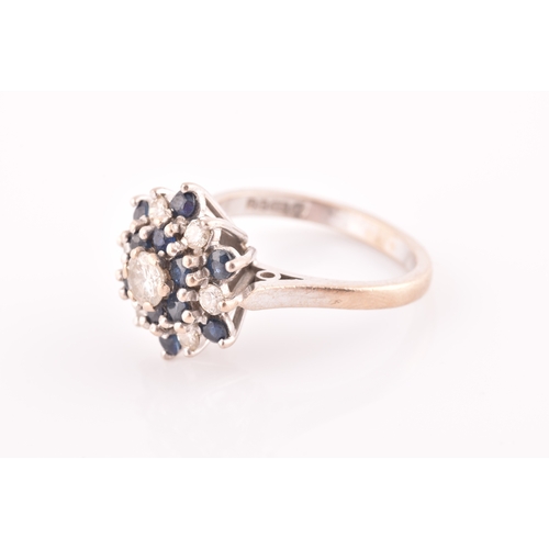 105 - An 18ct white gold, diamond, and sapphire cluster ring, centred with a round brilliant-cut diamond o... 