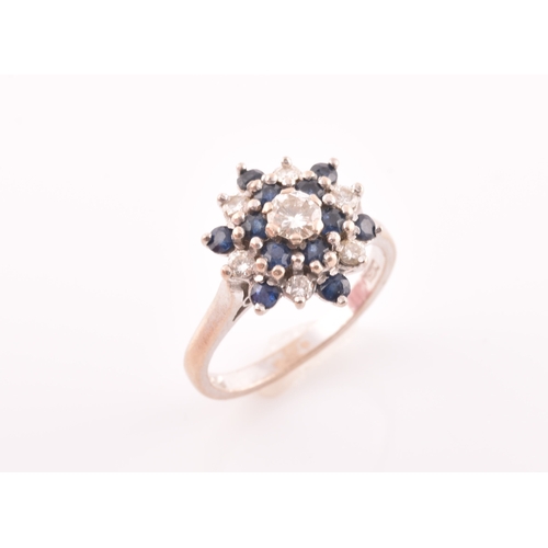 105 - An 18ct white gold, diamond, and sapphire cluster ring, centred with a round brilliant-cut diamond o... 