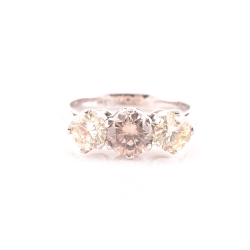 109 - An 18ct white gold and three stone diamond ring, centred with a pale fancy brown diamond flanked wit... 