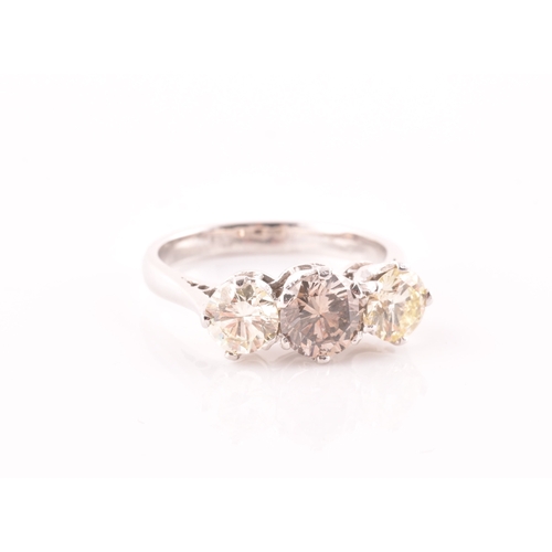 109 - An 18ct white gold and three stone diamond ring, centred with a pale fancy brown diamond flanked wit... 