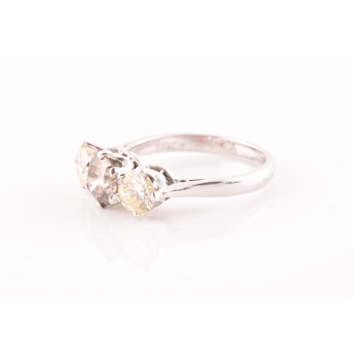 109 - An 18ct white gold and three stone diamond ring, centred with a pale fancy brown diamond flanked wit... 