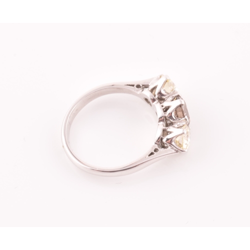 109 - An 18ct white gold and three stone diamond ring, centred with a pale fancy brown diamond flanked wit... 