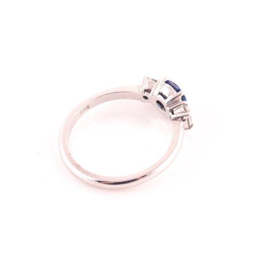 62 - An 18ct white gold, diamond, and sapphire ring, set with a mixed round-cut blue sapphire, flanked wi... 