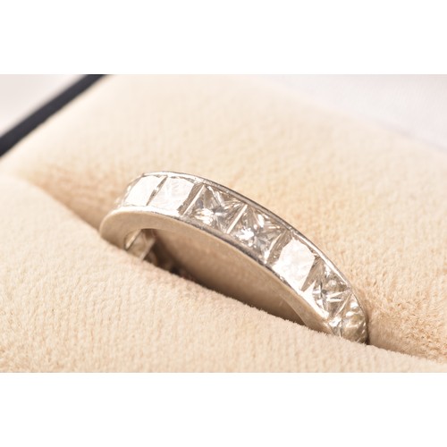 36 - A white metal diamond eternity ring, set with nineteen rectangular princess cut diamonds with an app... 