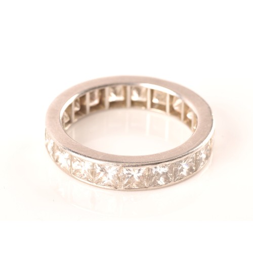 36 - A white metal diamond eternity ring, set with nineteen rectangular princess cut diamonds with an app... 