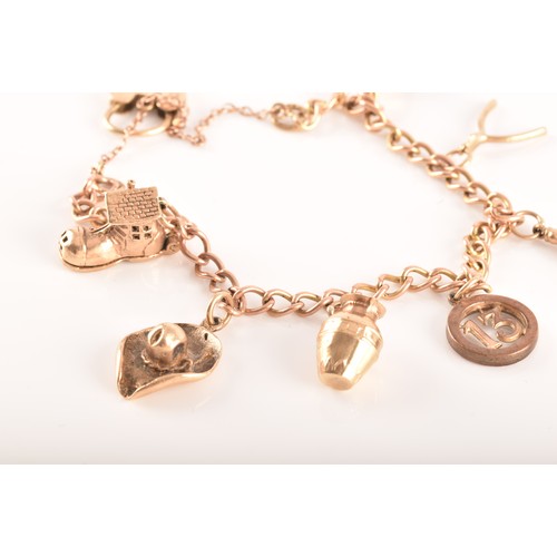 6 - A 9ct yellow gold curb link charm bracelet with seven charms, to include a boot charm, a hat charm, ... 