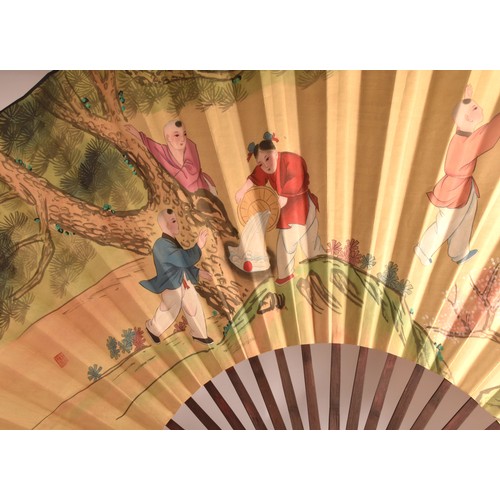 246 - A very large Chinese painted decorative display fan, painted with a scene of children playing by a t... 