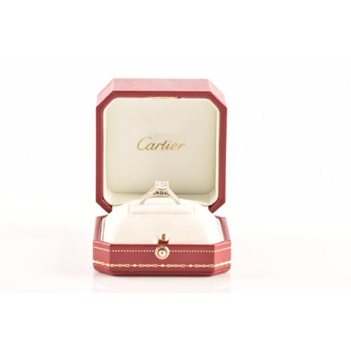 8 - Cartier. A platinum diamond flanked solitaire ring, set with a round brilliant cut diamond with an a... 