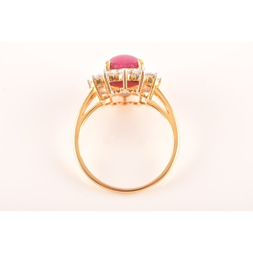 32 - A 18ct yellow gold cabochon ruby cluster ring, set with a central Burmese round cabochon ruby with a... 