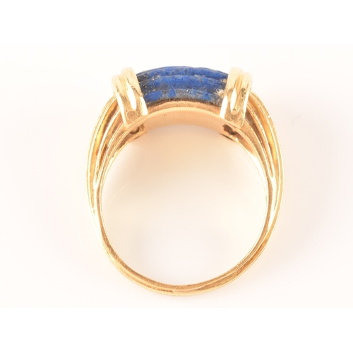 94 - An unusual Greek style yellow gold and lapis lazuli ring, set with ribbed lapis stone, with shaped r... 