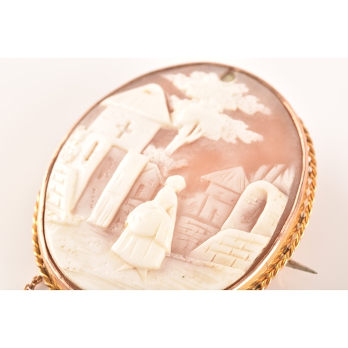 68 - A yellow metal mounted cameo brooch, the cameo depicting a woman in a long dress standing in a rural... 