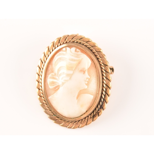 68 - A yellow metal mounted cameo brooch, the cameo depicting a woman in a long dress standing in a rural... 