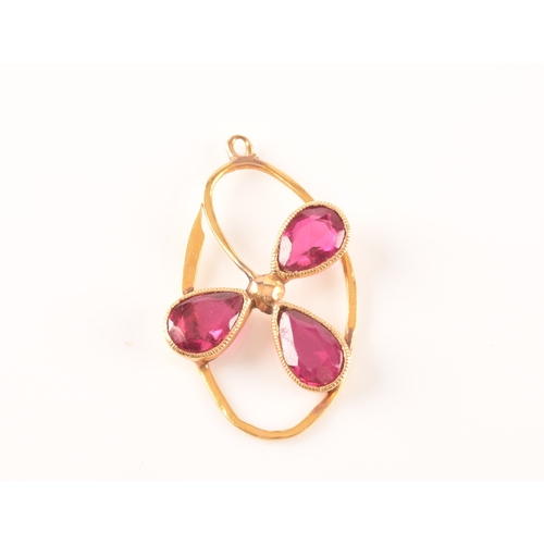 69 - A yellow metal and red stone clover bar brooch, set with two stones, unmarked, 1.7 cm long, together... 