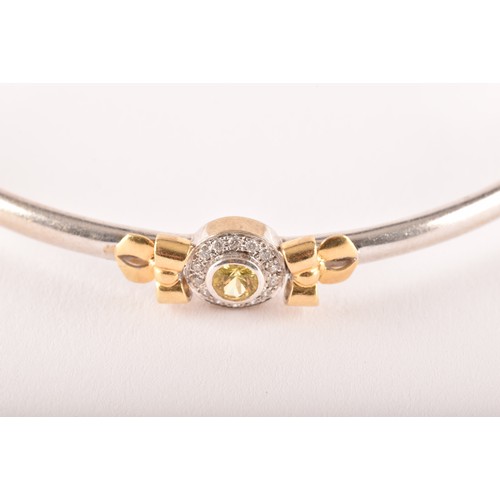 95 - Theo Fennell. A 18ct white and yellow gold  bangle set with a round brilliant cut yellow sapphire wi... 