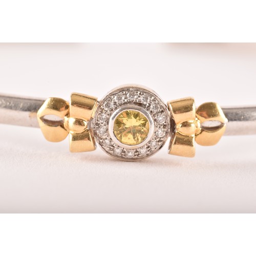 95 - Theo Fennell. A 18ct white and yellow gold  bangle set with a round brilliant cut yellow sapphire wi... 