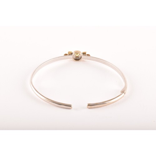 95 - Theo Fennell. A 18ct white and yellow gold  bangle set with a round brilliant cut yellow sapphire wi... 